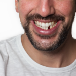 A man smiles, showing his missing front lower tooth.